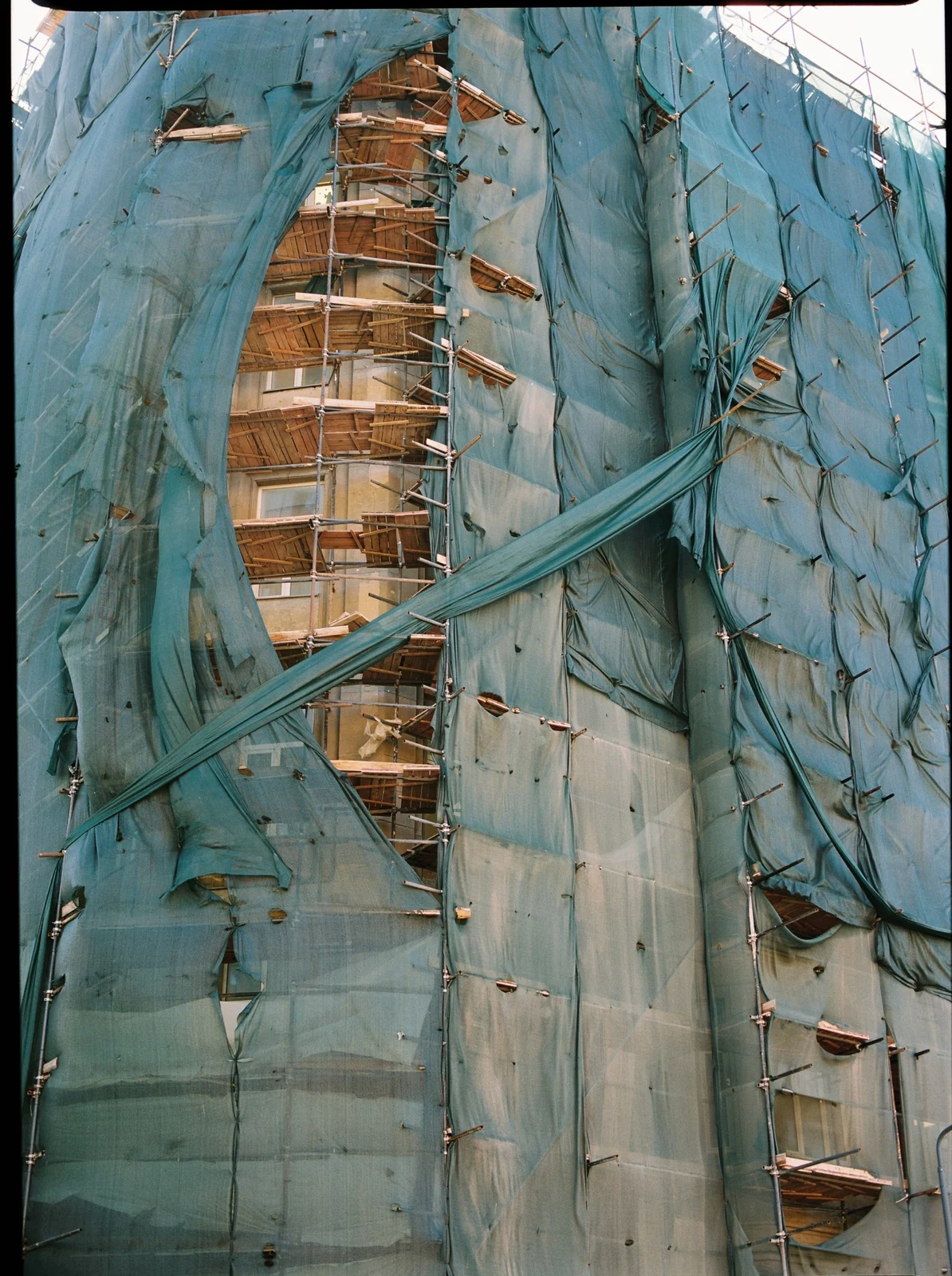 Building wrapped in torn green mesh